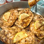 chicken and lemon in a skillet with a drizzle of honey