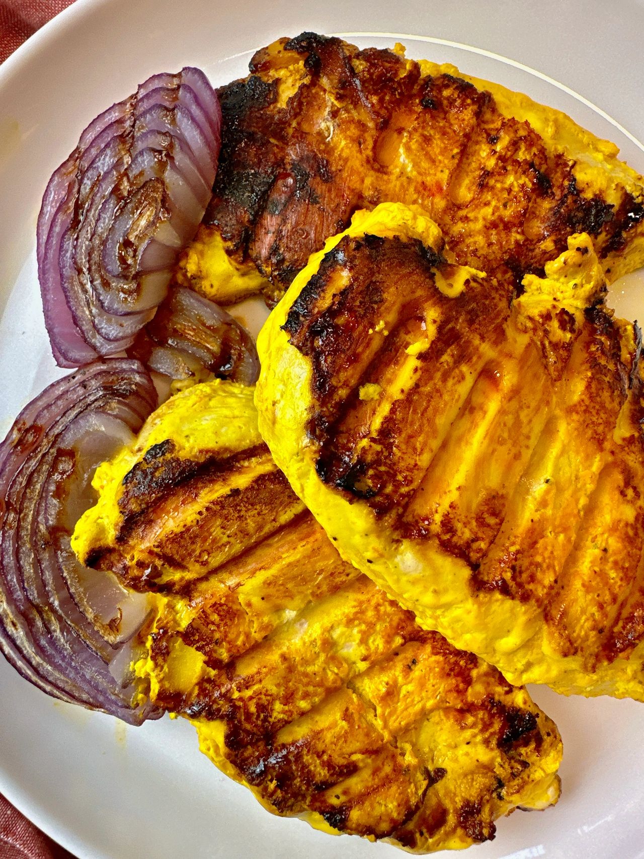 saffron chicken and red onion on a white plate