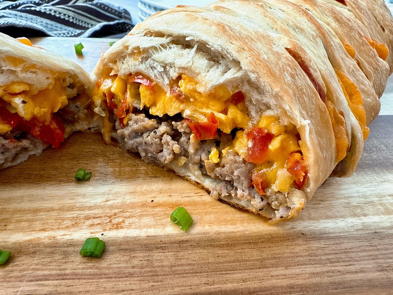breakfast braid with eggs, cheese and sausage on a wooden cutting board