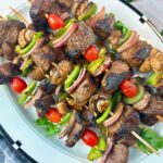 beef and vegetable kebabs on a white serving plate