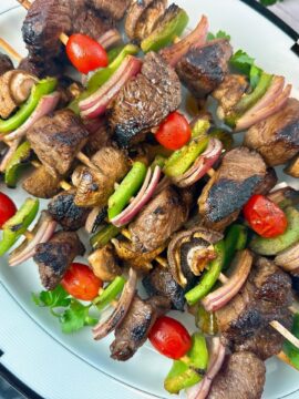 beef and vegetable kebabs on a white serving plate