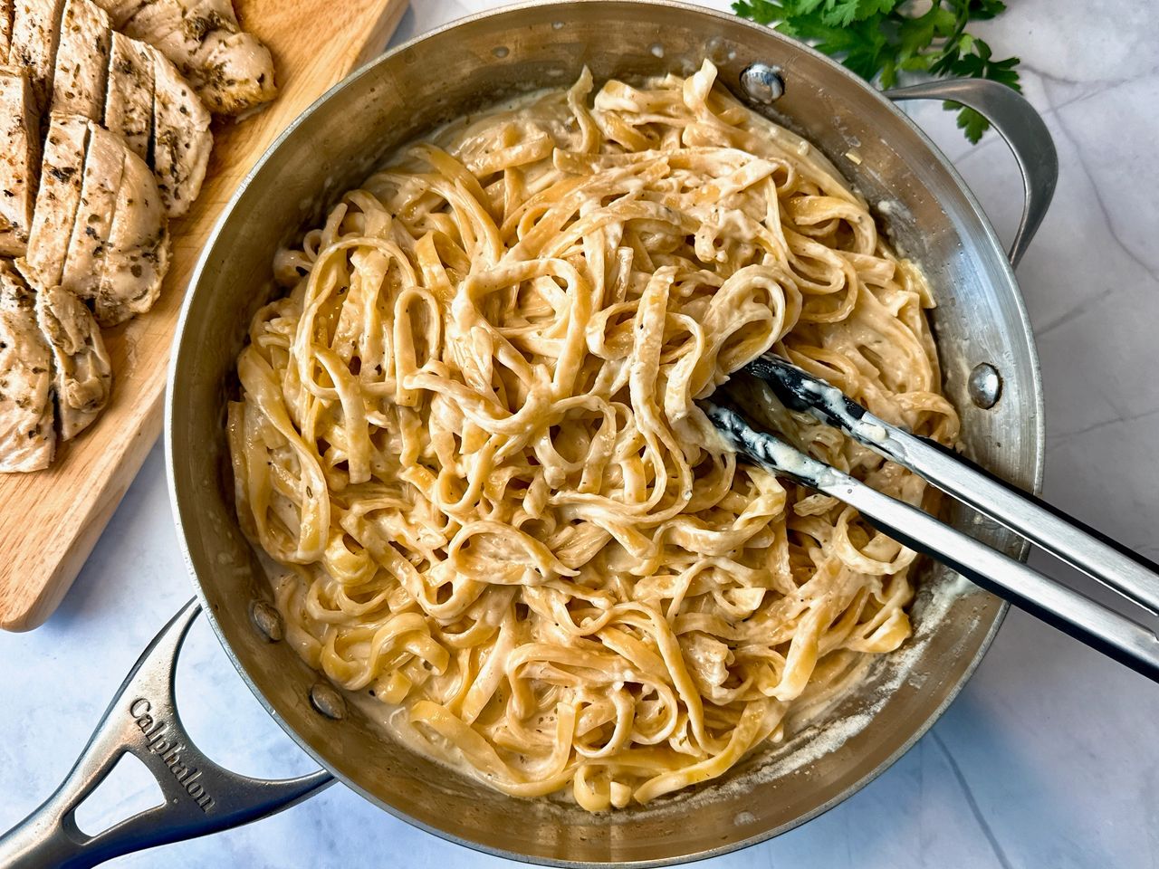 chicken alfredo in a skillet and on a cutting board