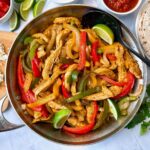 chicken and bell peppers in a skillet with tortillas on the side