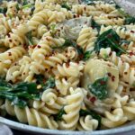 pasta with spinach and artichoke hearts in a skillet