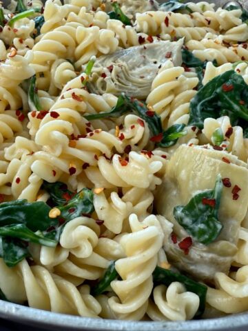 pasta with spinach and artichoke hearts in a skillet