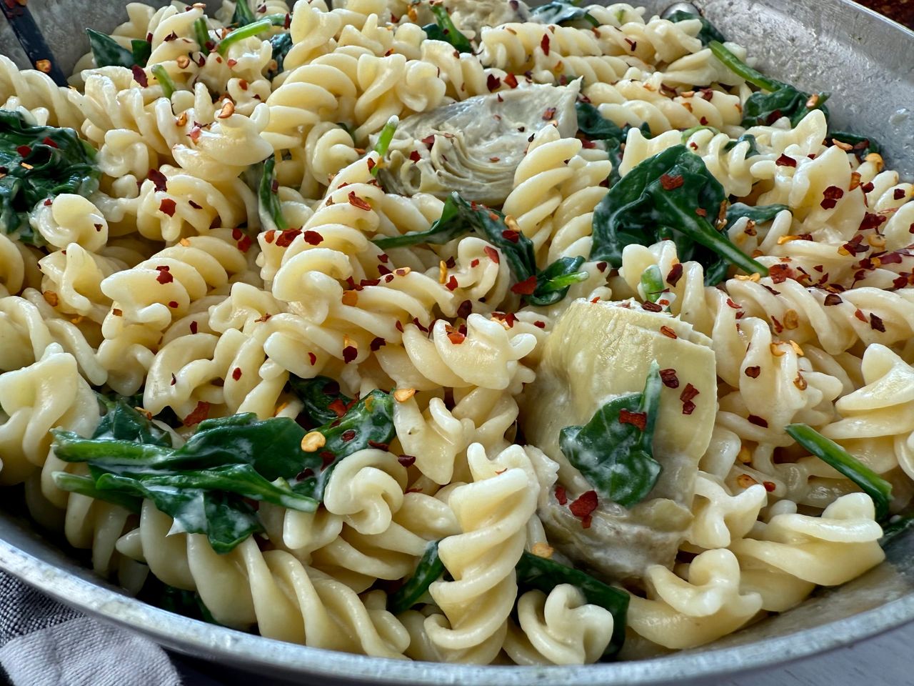 pasta with spinach and artichoke hearts in a skillet