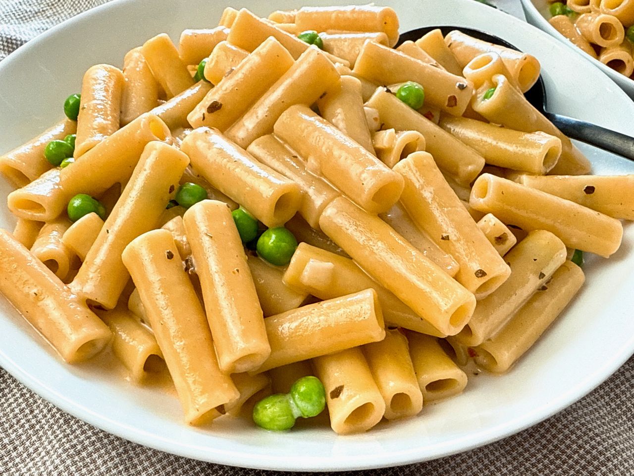 pasta and peas in a cream sauce in a white bowl