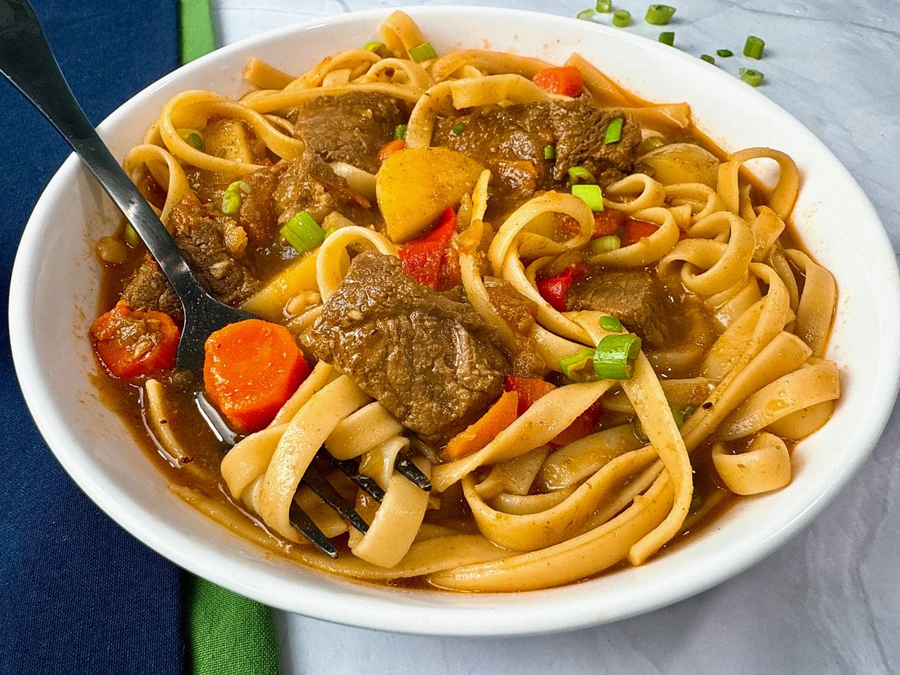 beef and noodle stir fry in a white bowl