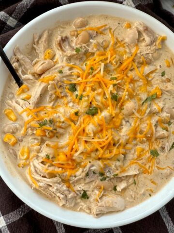 white chicken chili in a white bowl on a brown kitchen towel