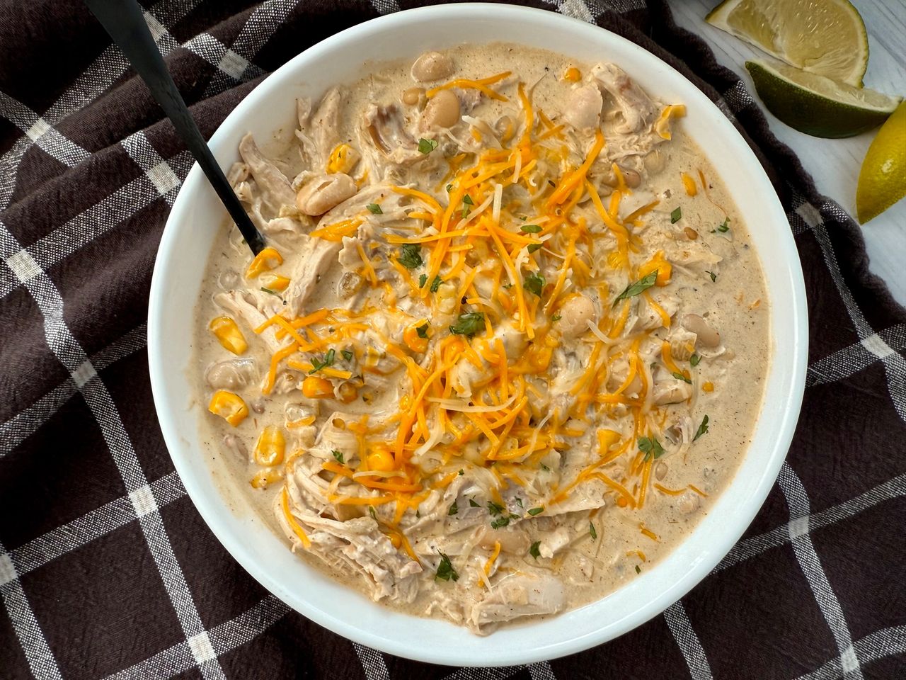 white chicken chili in a white bowl on a brown kitchen towel