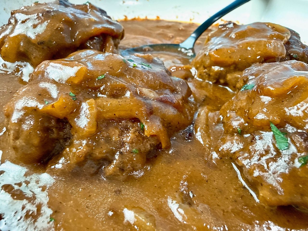 hamburger steaks and gravy with a black serving spoon