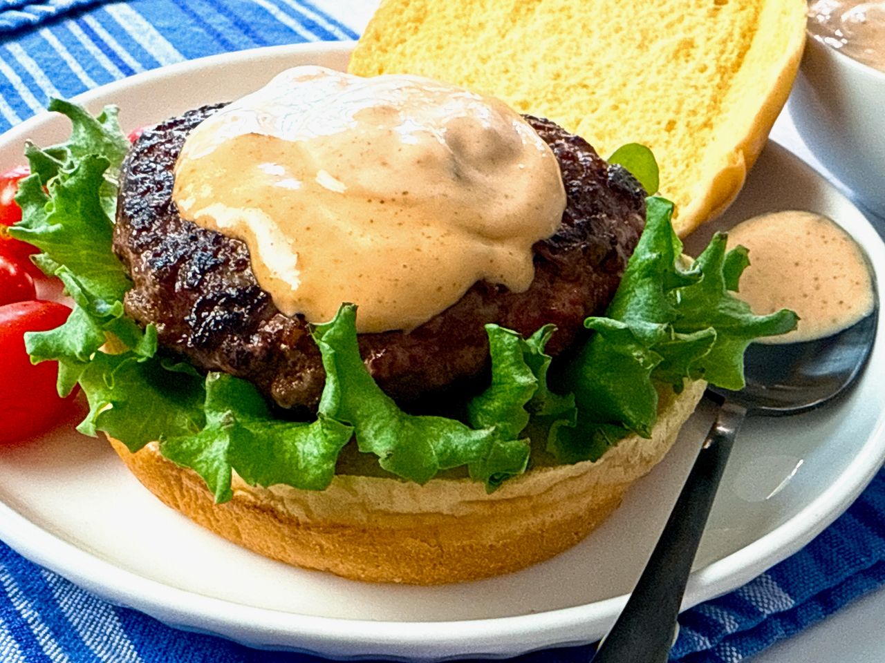 burger on a bun with lettuce and spicy sauce