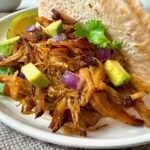 pork carnitas with avocado on a white plate
