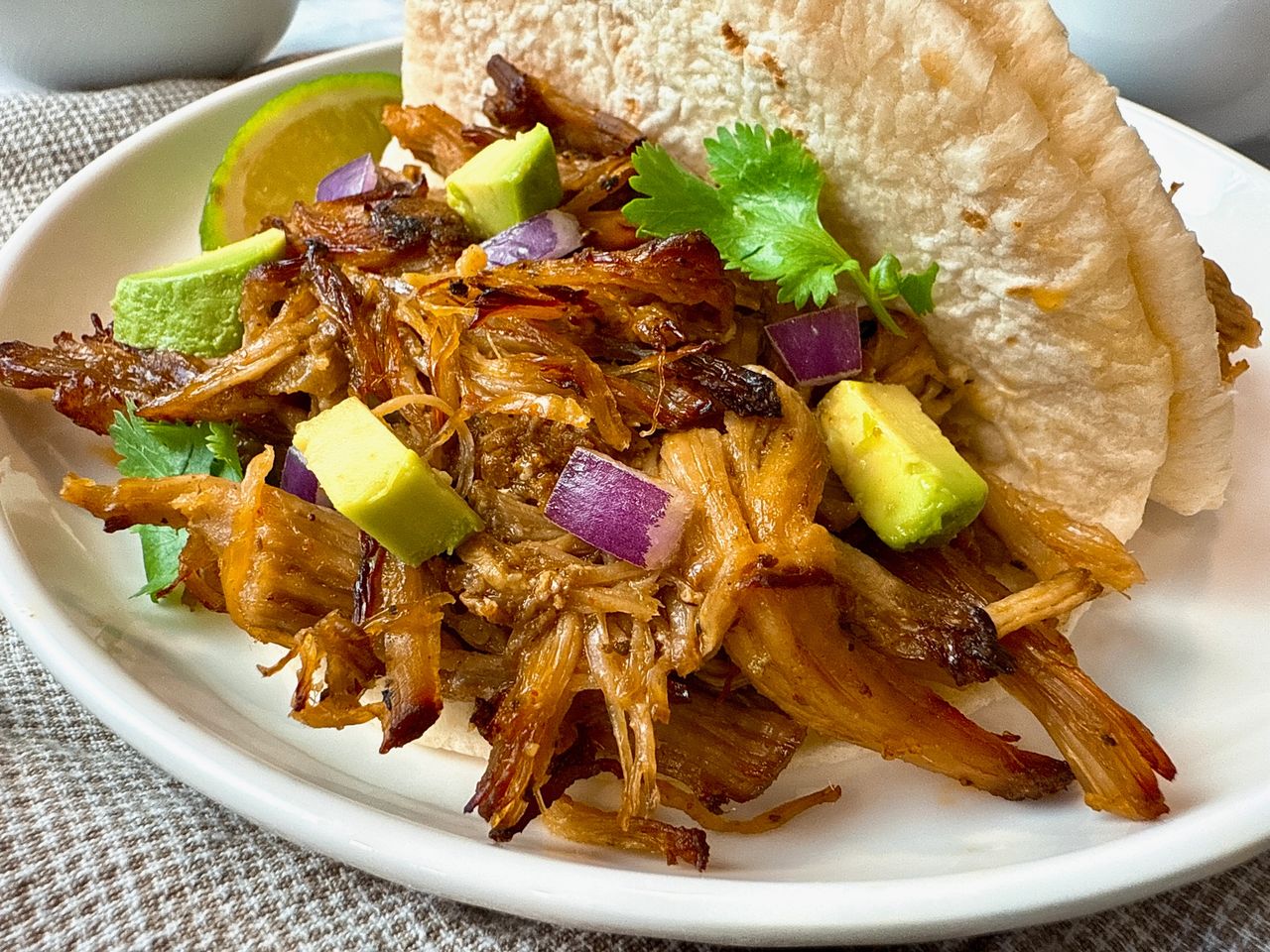 Carnitas pork carnitas with avocado on a white plate