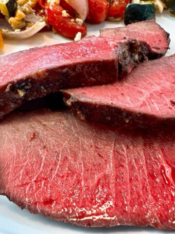 sirloin tip roast on a white plate with vegetables