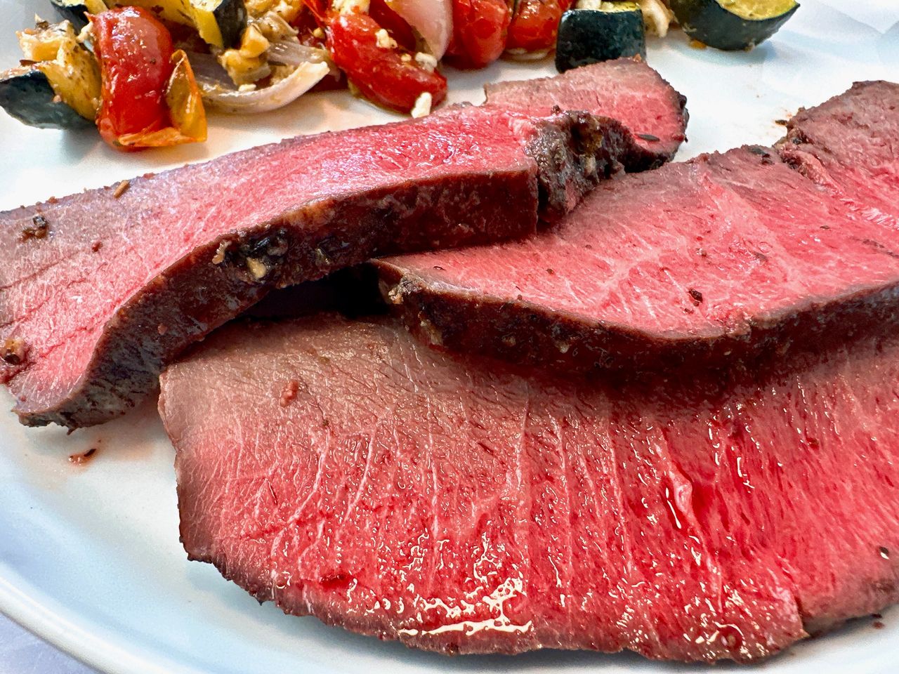 sirloin tip roast on a white plate with vegetables