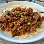 Ground beef and chili crisp over rice in a white bowl