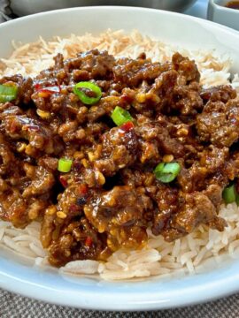 Ground beef and chili crisp over rice in a white bowl
