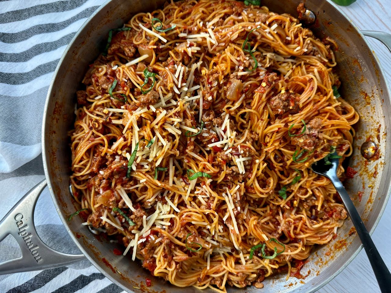 pasta bolognese in a silver pan with a black spoon