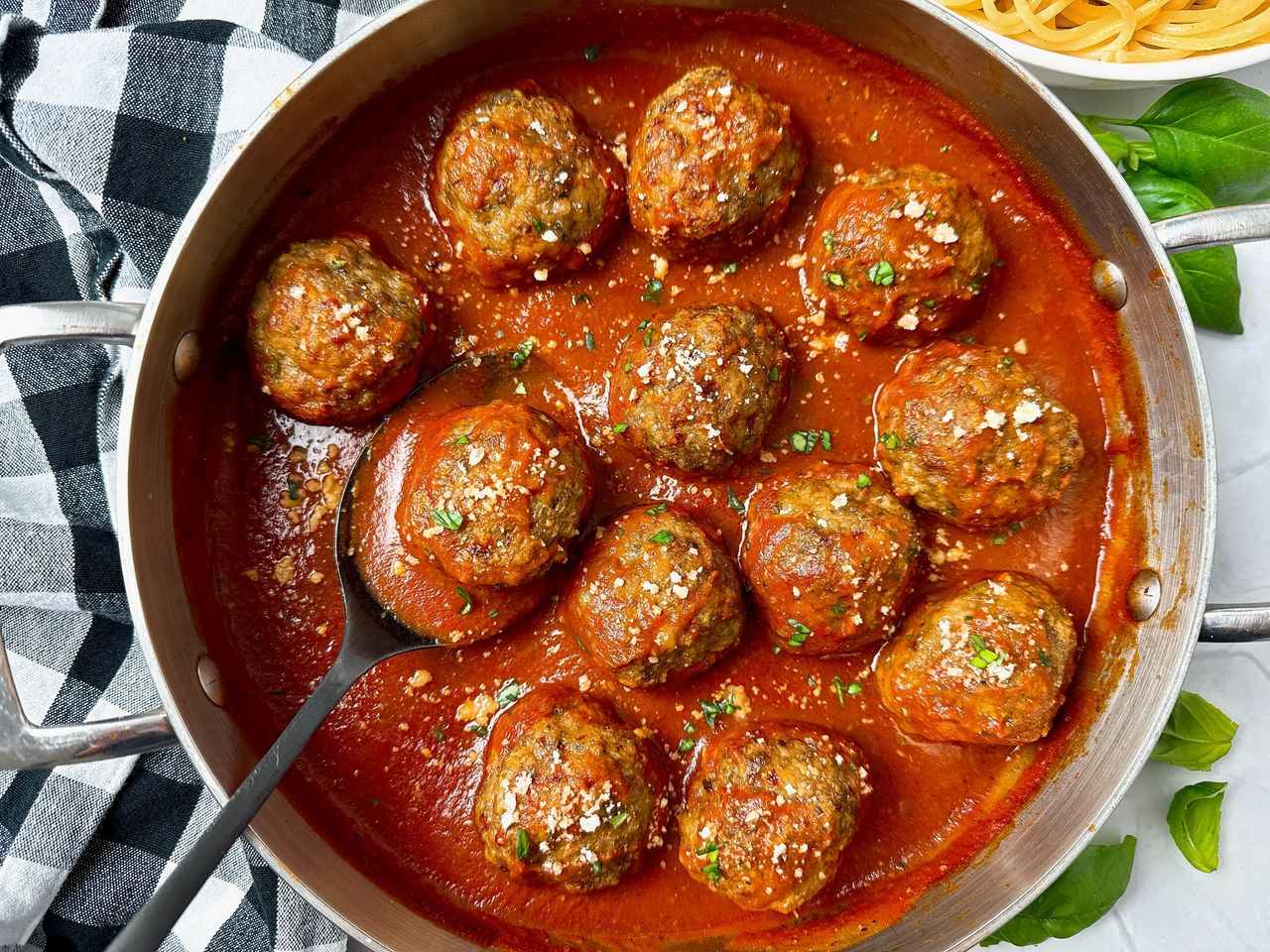 meatballs and marinara sauce in a pan with a black serving spoon