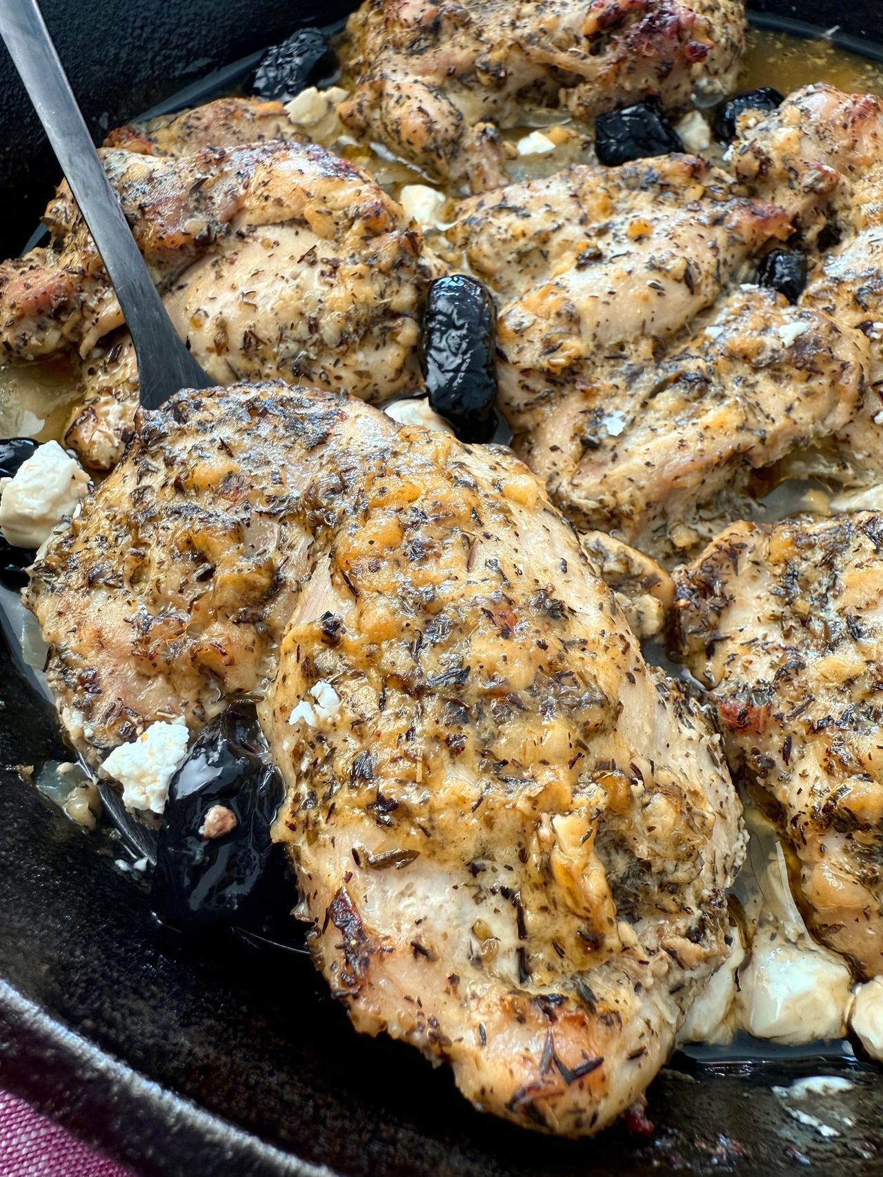 chicken thighs in a cast iron skillet with feta and olives