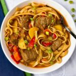 beef and noodle stir fry in a white bowl