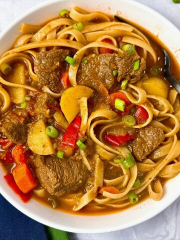 beef and noodle stir fry in a white bowl