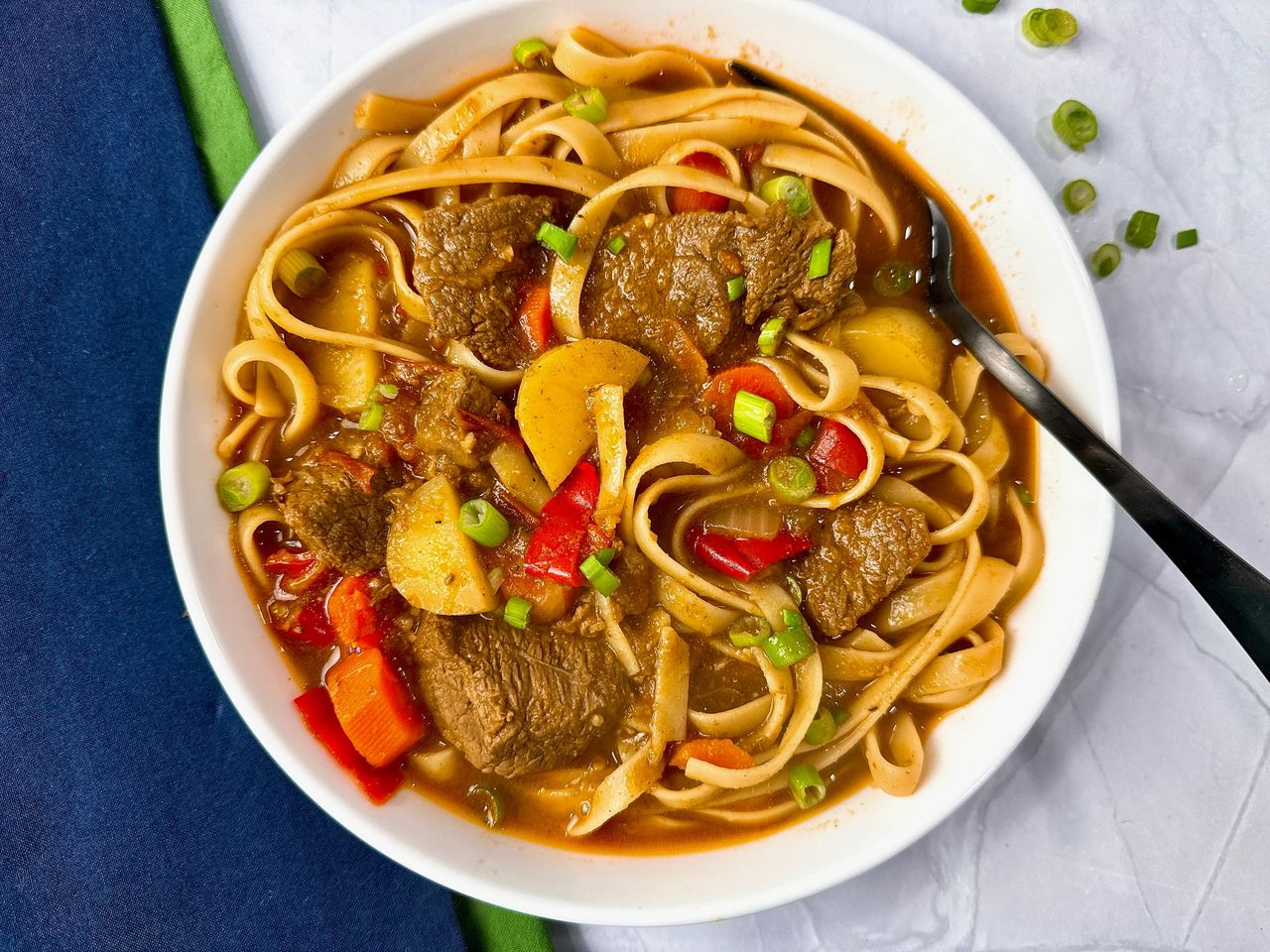 beef and noodle stir fry in a white bowl