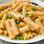 pasta and peas in a cream sauce in a white bowl