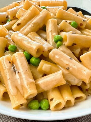 pasta and peas in a cream sauce in a white bowl