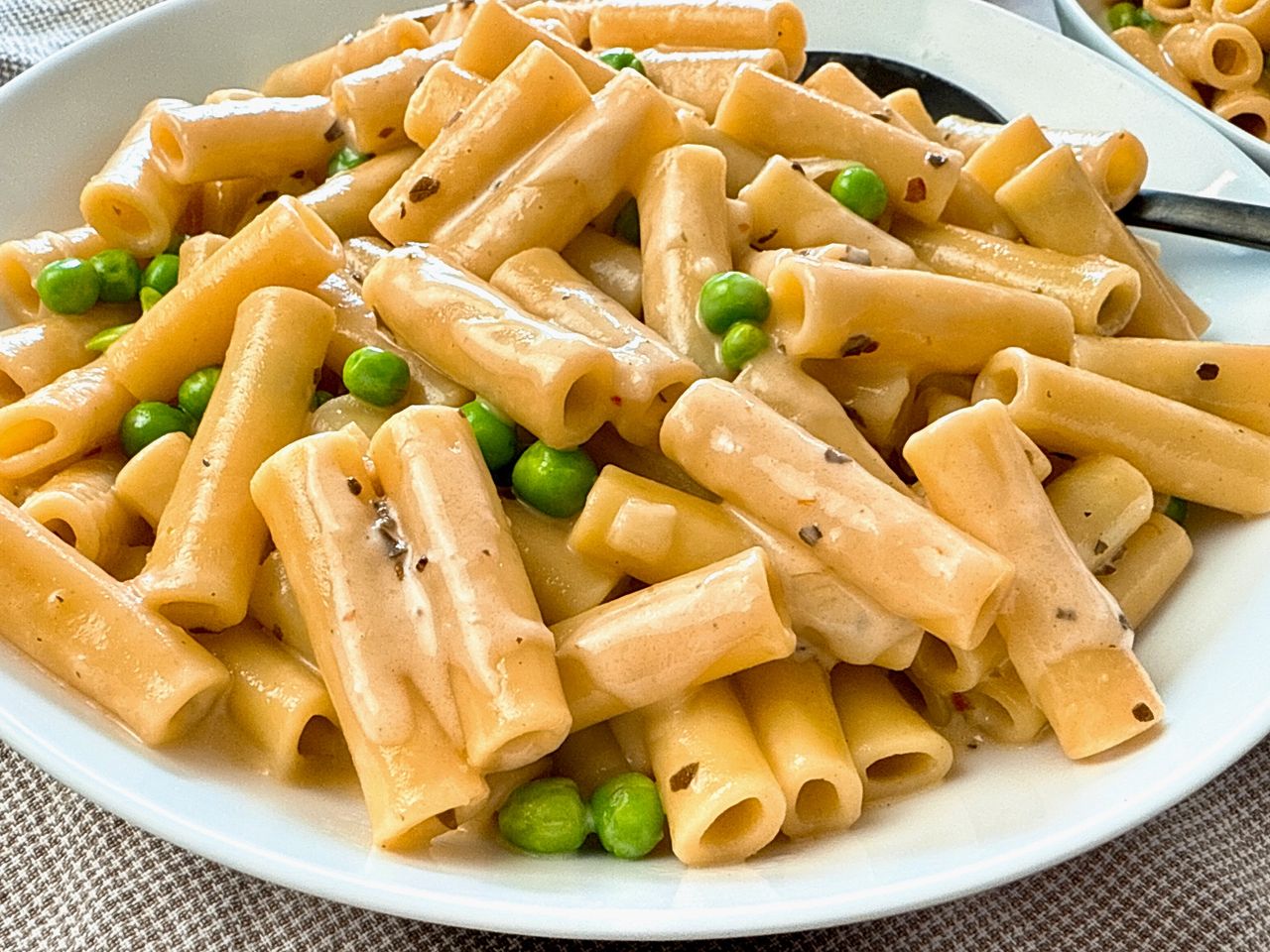 pasta and peas in a cream sauce in a white bowl