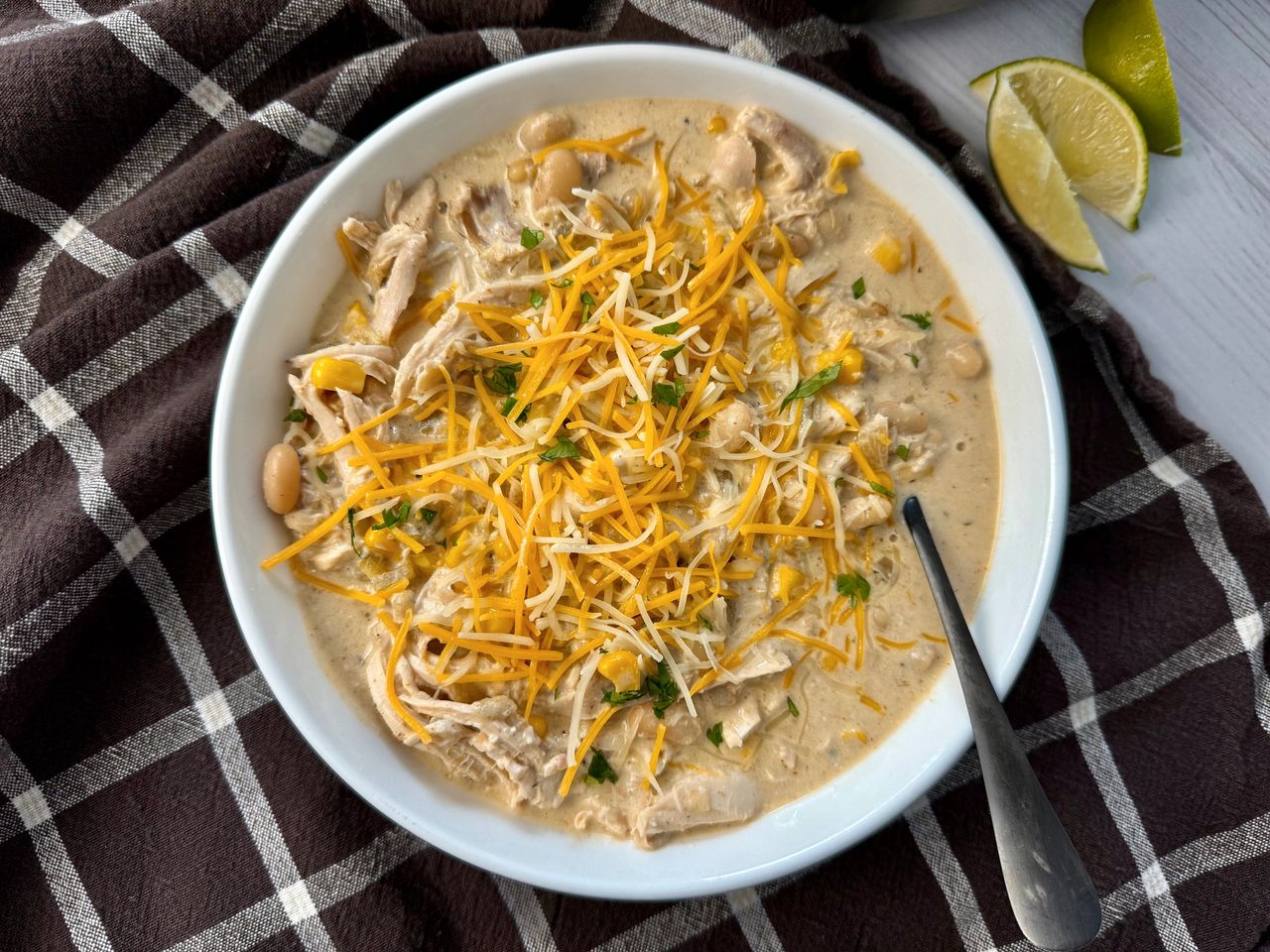 white chicken chili in a white bowl on a brown kitchen towel