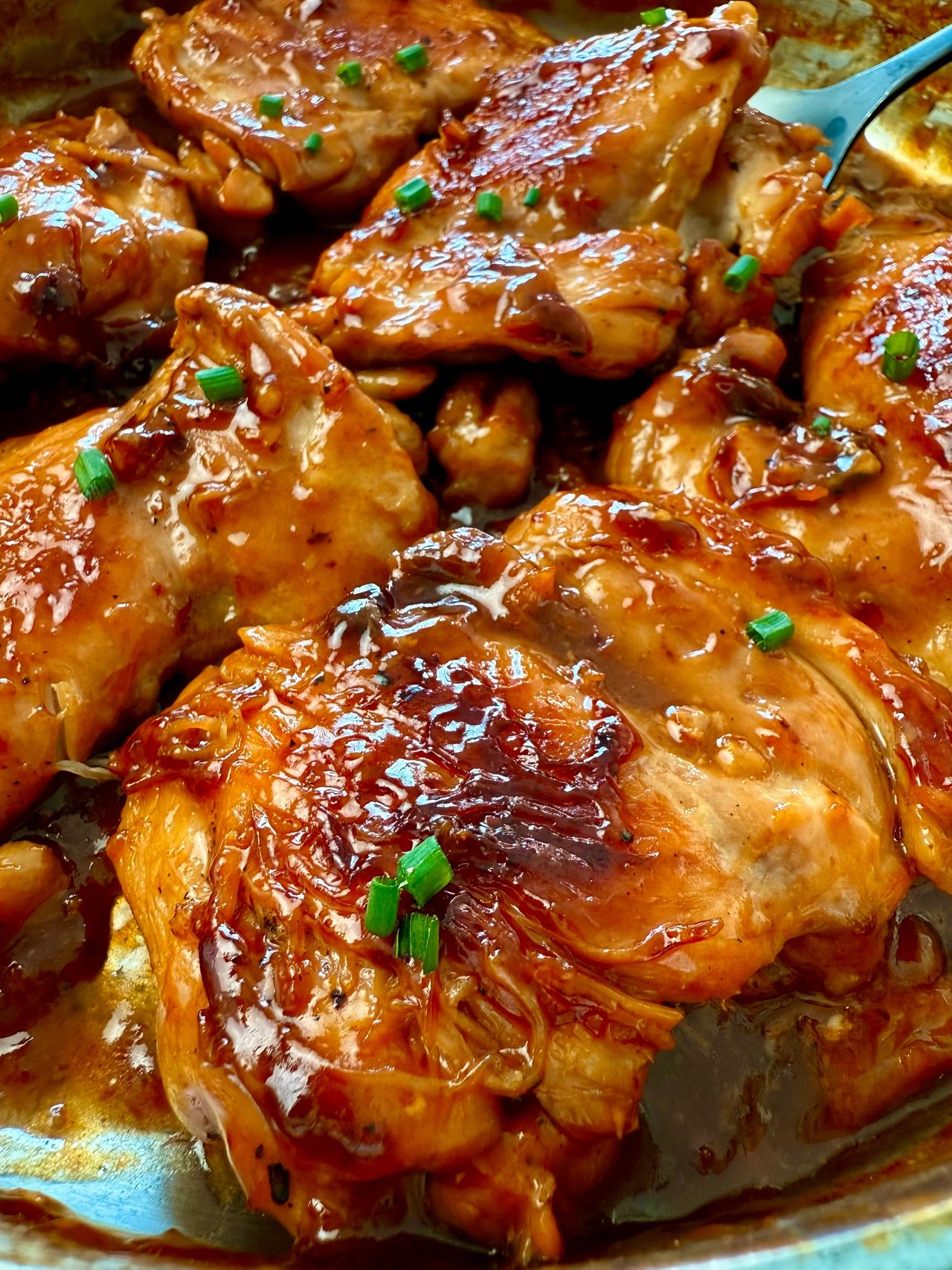 teriyaki chicken in a pan with a serving spoon