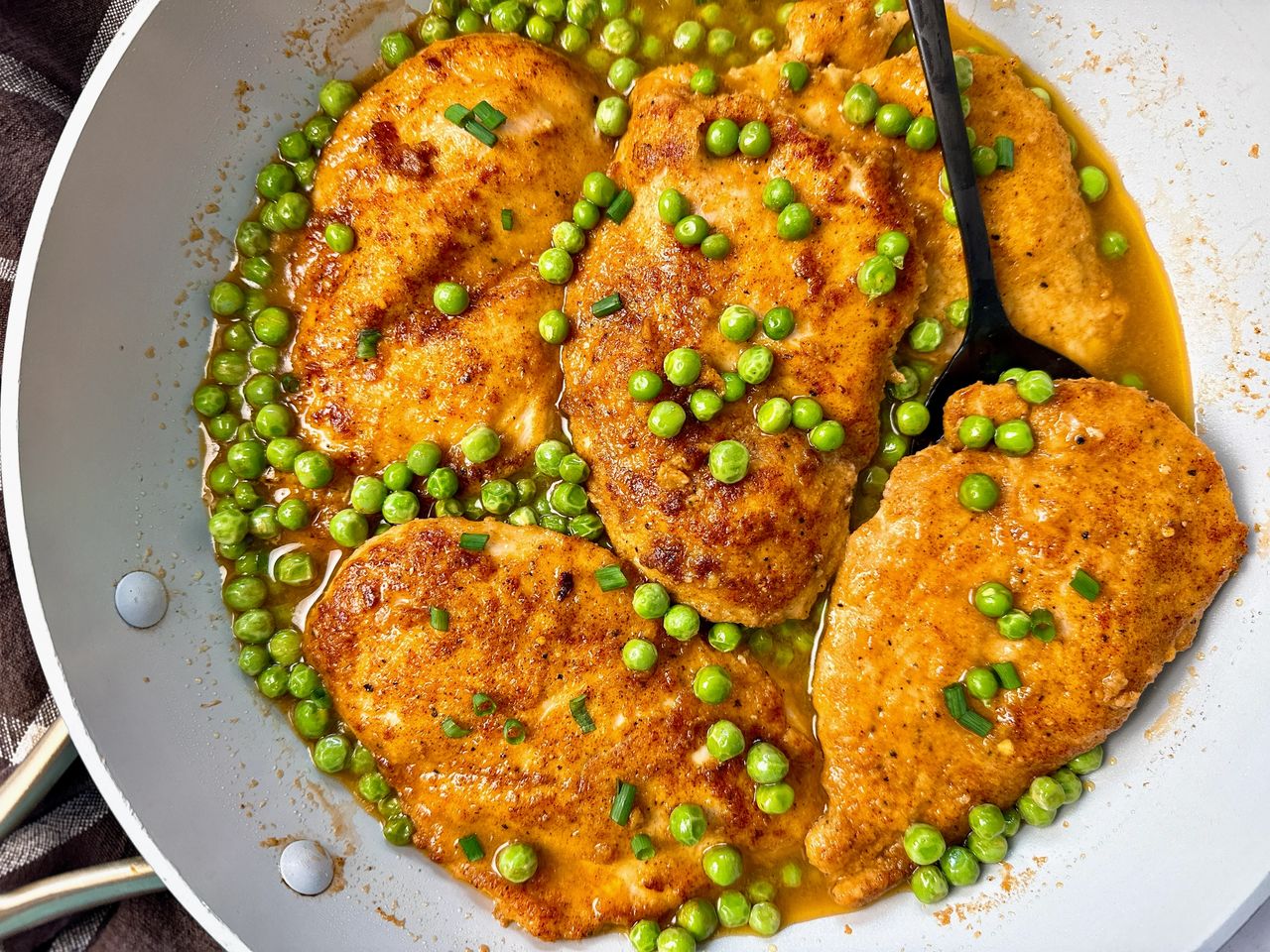 parmesan chicken and peas in wine sauce in white skillet