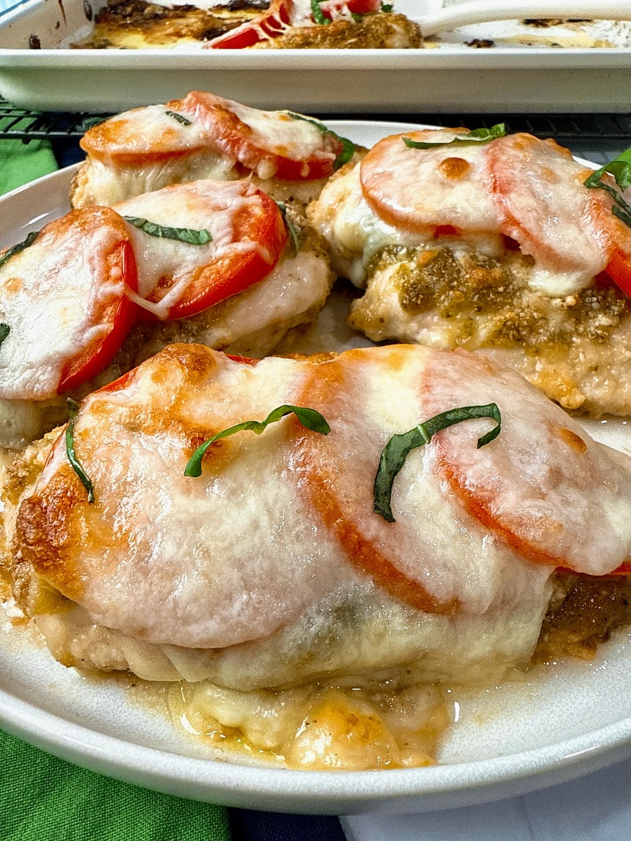 baked chicken with cheese and tomatoes on a white plate
