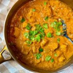 chicken curry topped with cilantro in a silver pan