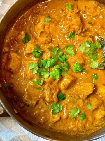 chicken curry topped with cilantro in a silver pan