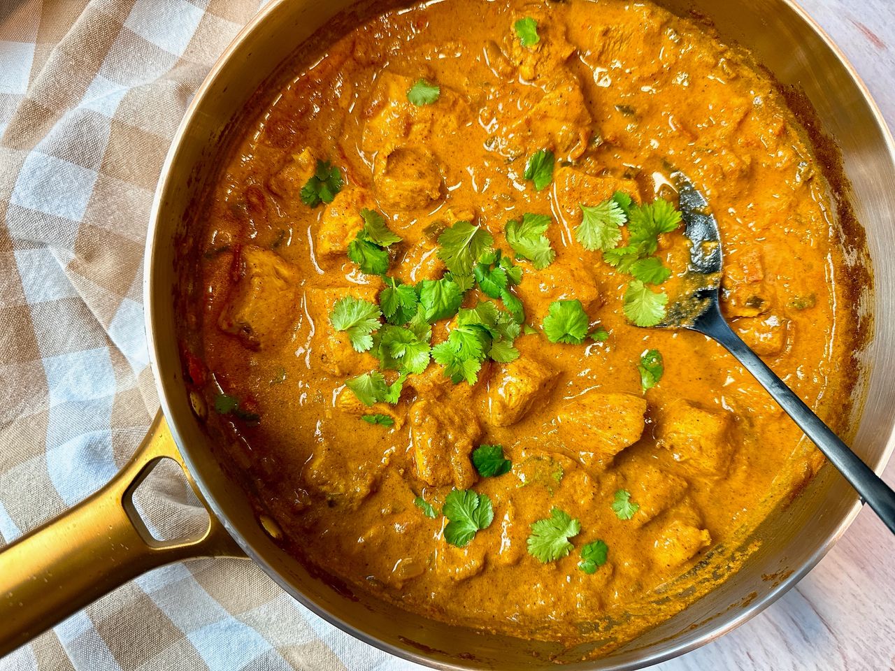 chicken curry topped with cilantro in a silver pan