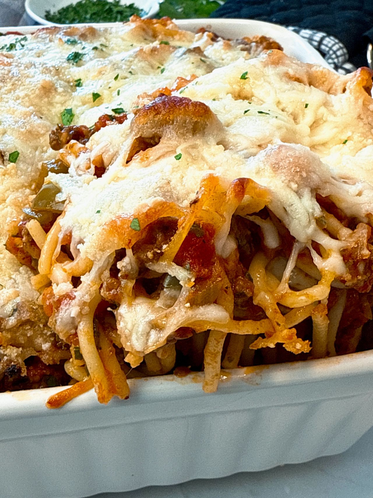 baked spaghetti in a baking dish with a black spoon