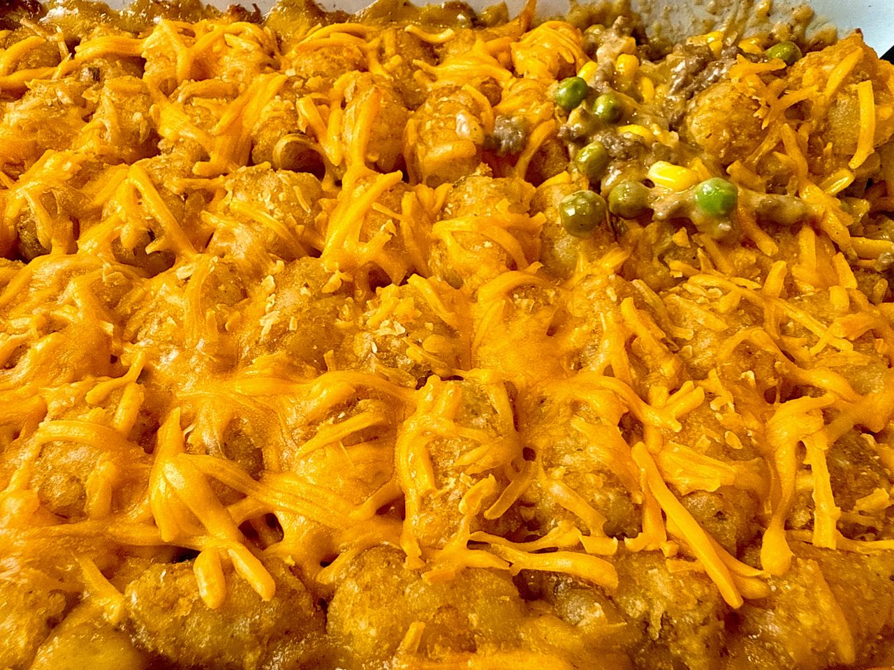 tater tot casserole in a white baking dish and on a spoon
