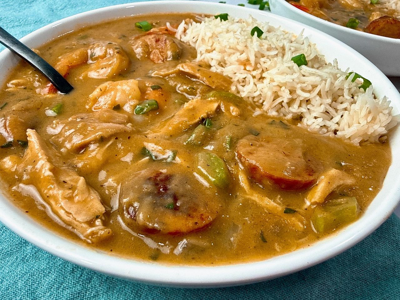 Cajun gumbo and rice in a white bowl with a black spoon