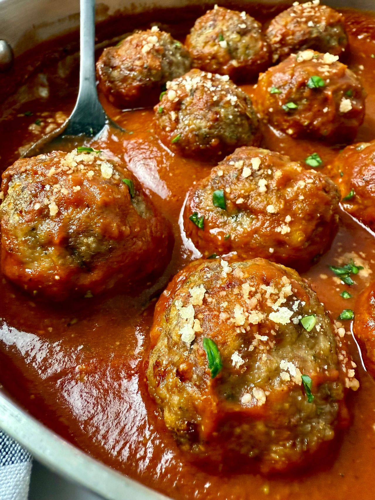 meatballs and marinara sauce in a pan with a black serving spoon
