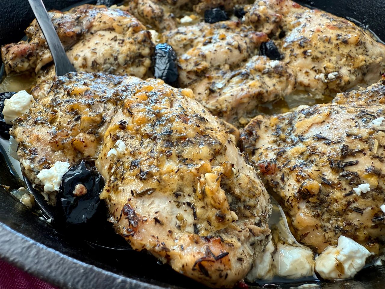 chicken thighs in a cast iron skillet with feta and olives