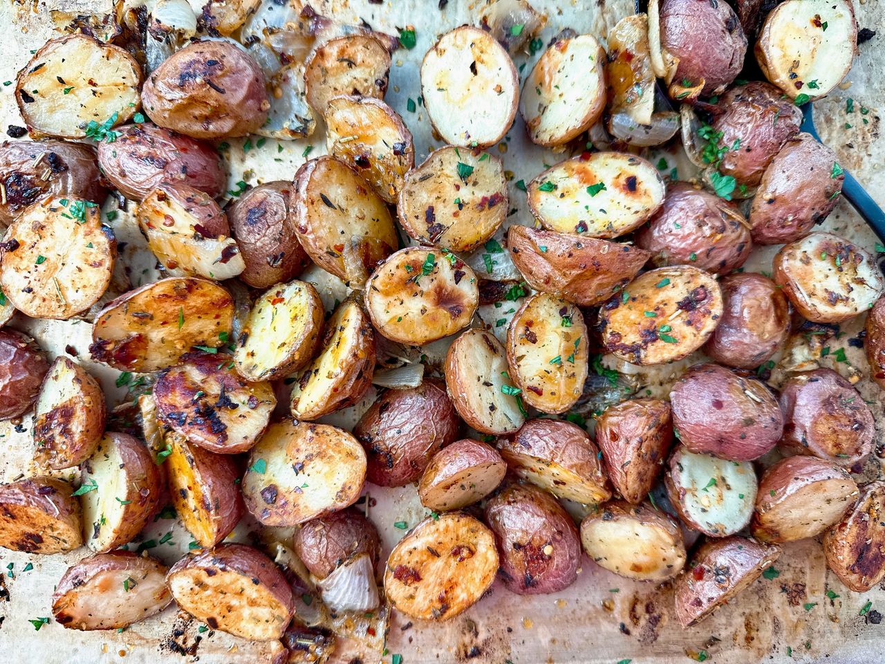garlic roasted potatoes and onions on a baking sheet