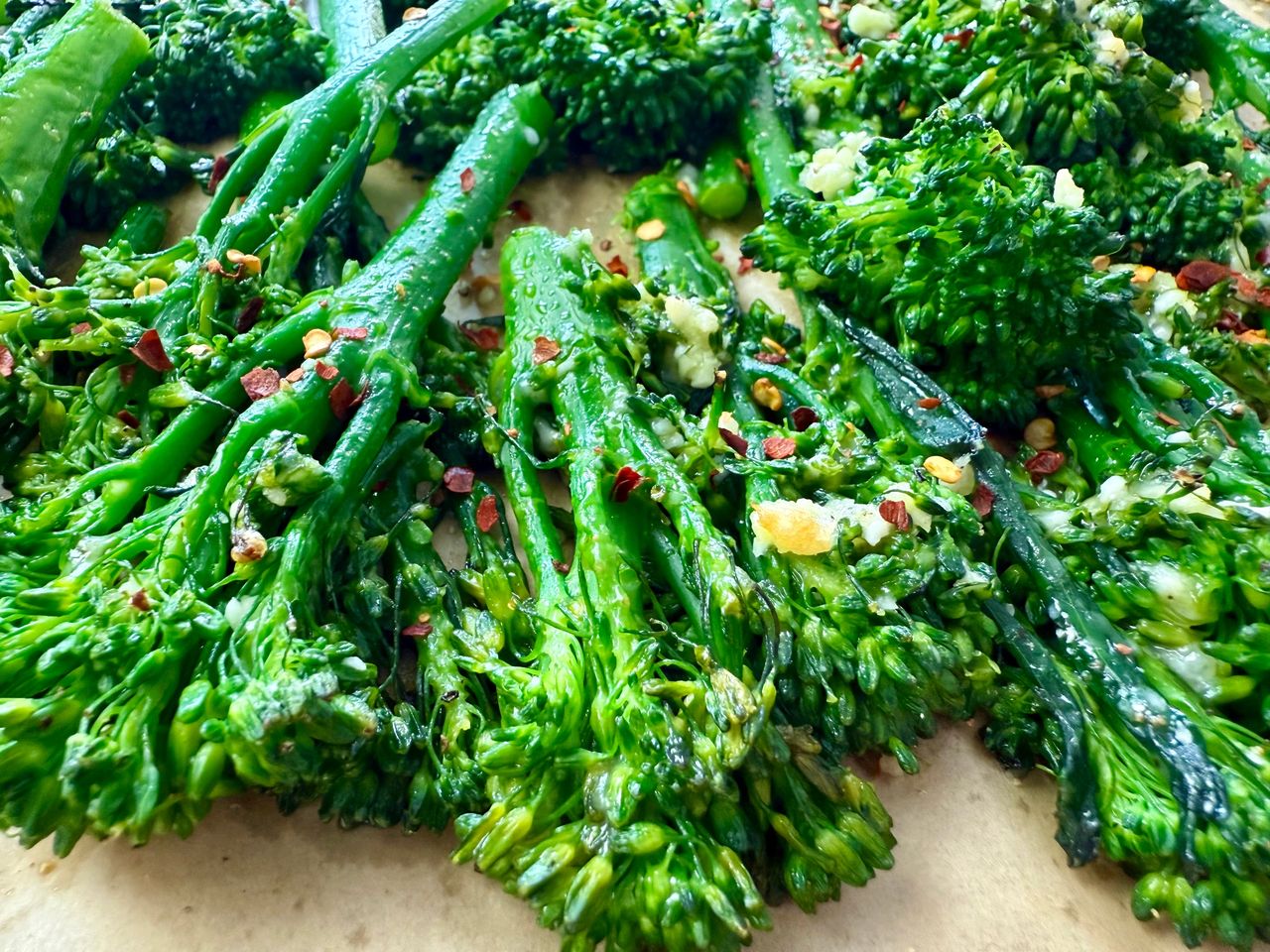 broccolini and red pepper flakes on a parchment paper lined baking sheet