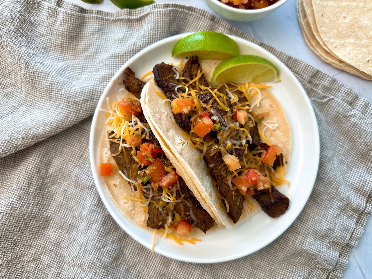 steak street tacos on a white plate with lime garnish