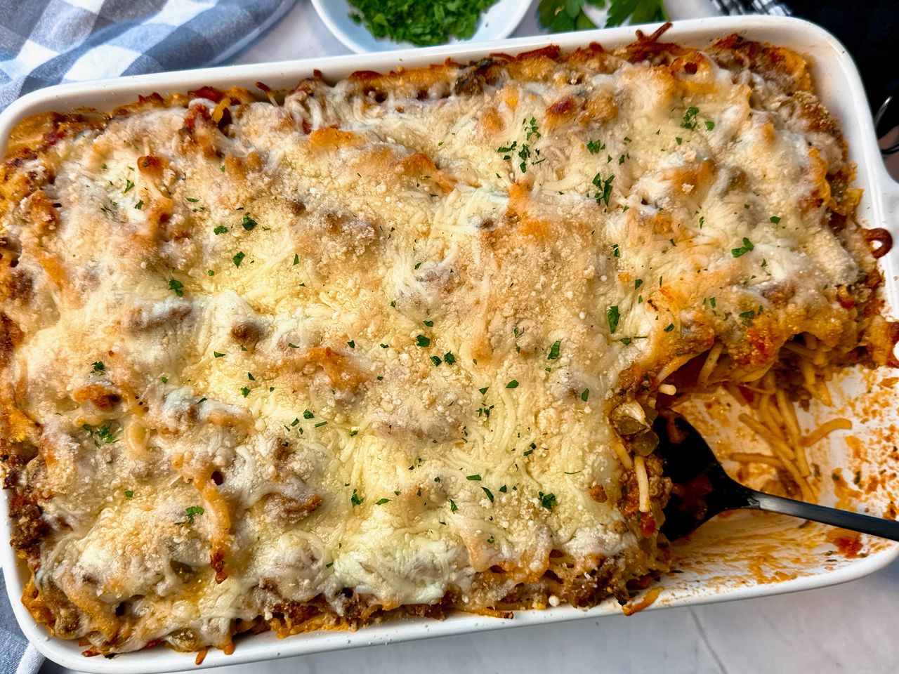 baked spaghetti in a baking dish with a black spoon