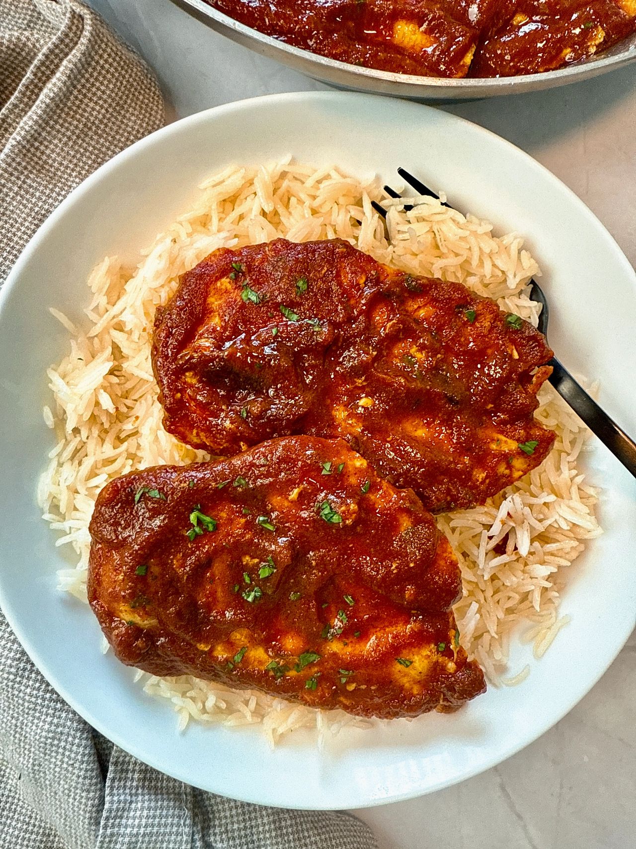 chicken with enchilada sauce over rice on a white plate