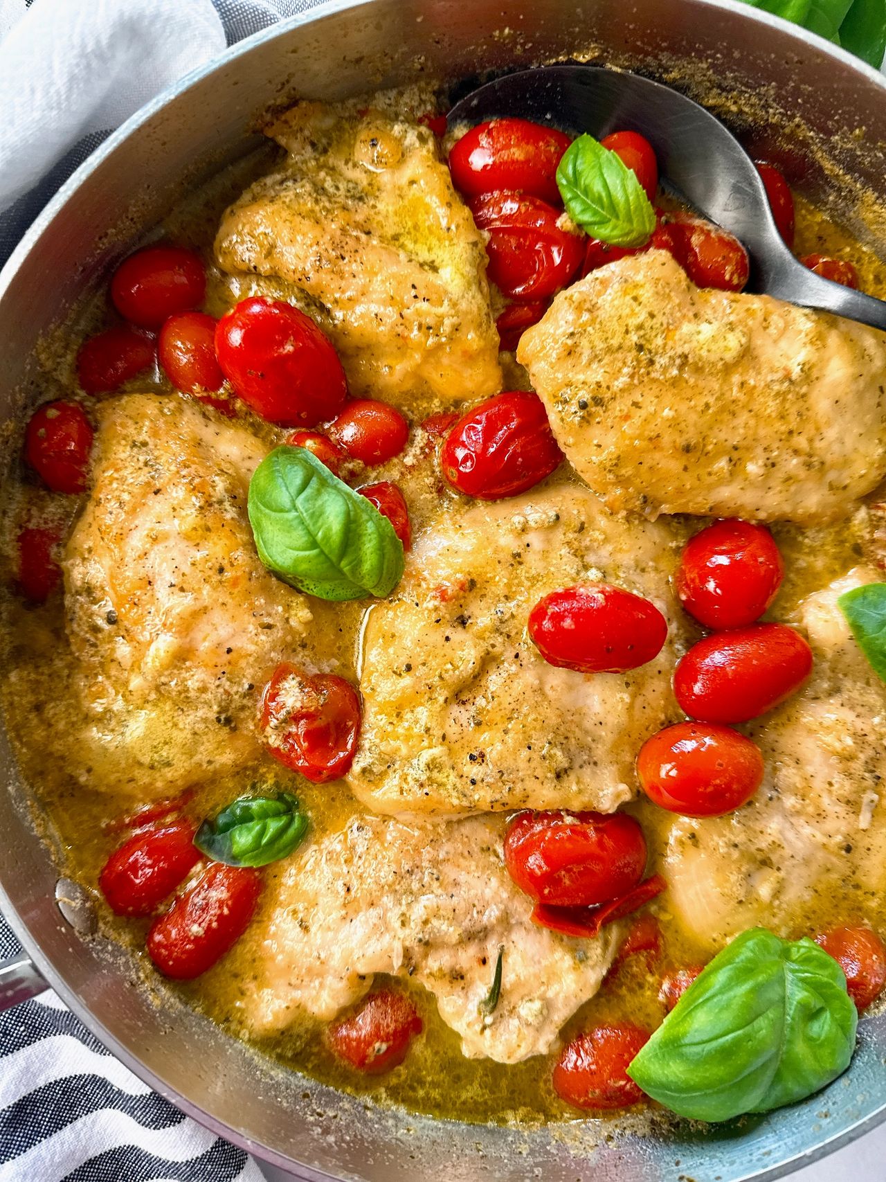 chicken and grape tomatoes with pesto in a silver pan