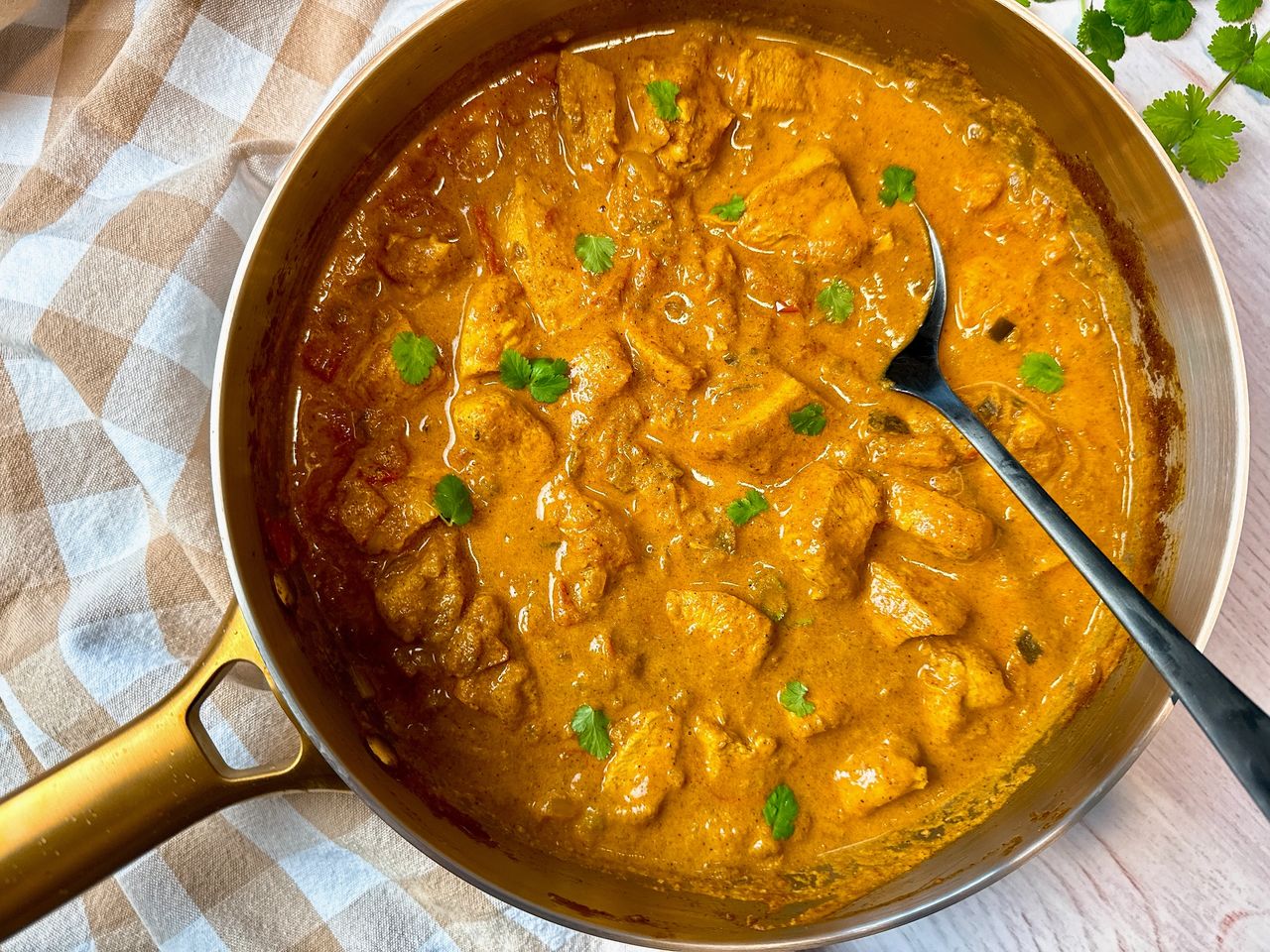 chicken curry topped with cilantro in a silver pan